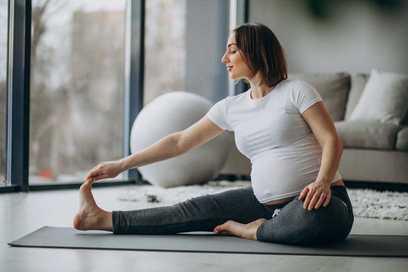 Schwangere dehnt sich zu Pilates Übung